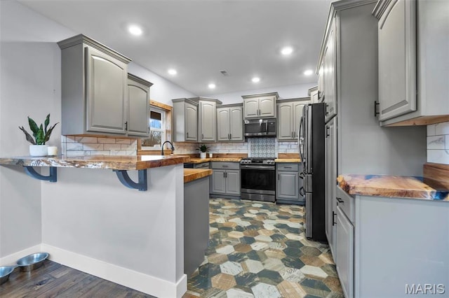 284 Ridge Rd, Oak Ridge, MO 63769 - kitchen featuring gray cabinets, appliances with stainless steel finishes, a peninsula, a breakfast bar area, and decorative backsplash