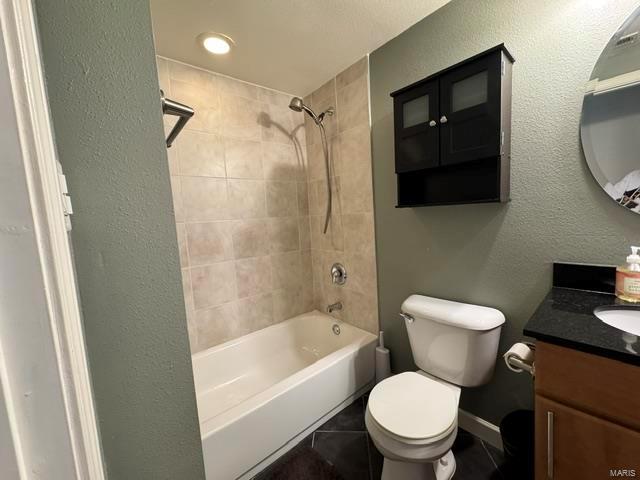 bathroom with toilet, vanity, tile patterned floors, and shower / tub combination