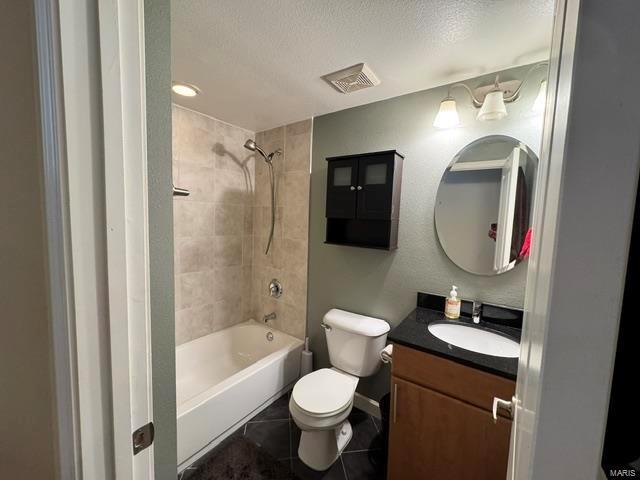 bathroom featuring tile patterned flooring, toilet, vanity, a textured ceiling, and shower / bath combination