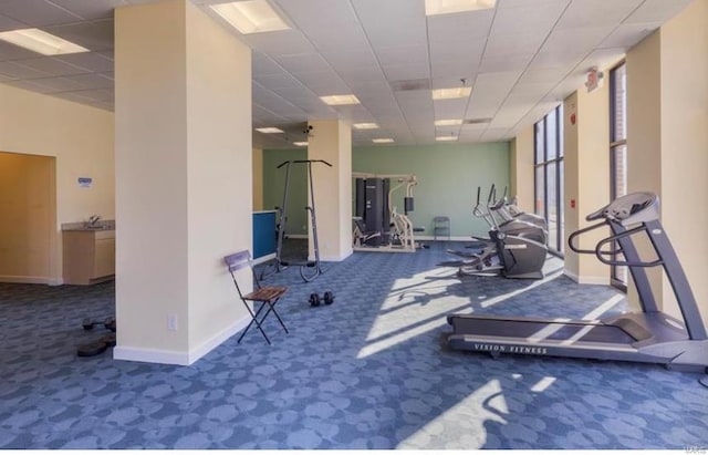exercise room with carpet, baseboards, and a paneled ceiling