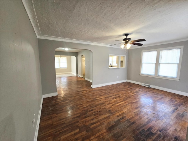 unfurnished living room featuring arched walkways, ceiling fan, dark wood finished floors, a textured ceiling, and baseboards