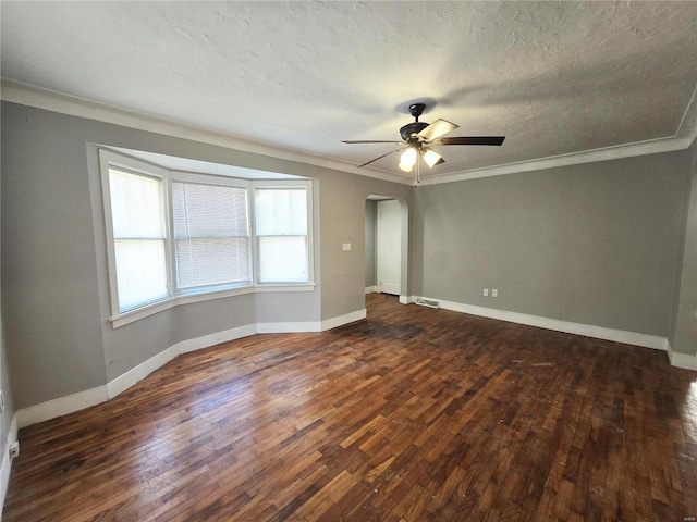empty room featuring ornamental molding, arched walkways, hardwood / wood-style floors, a ceiling fan, and a textured ceiling