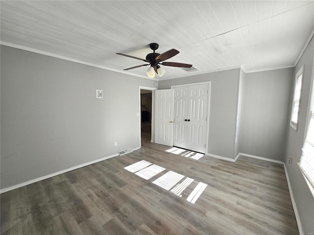 unfurnished bedroom with crown molding, multiple windows, wood finished floors, baseboards, and a ceiling fan