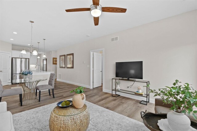 living room with light wood-style floors, baseboards, a ceiling fan, and recessed lighting