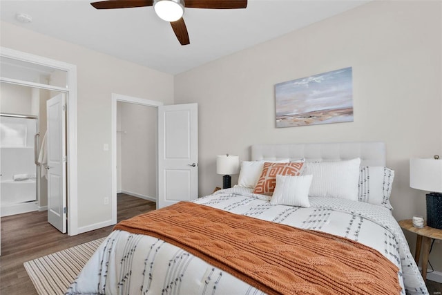 bedroom featuring wood finished floors, ceiling fan, baseboards, and a walk in closet