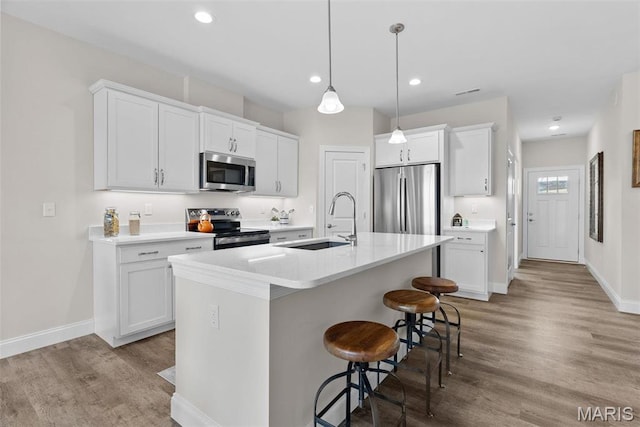 889 Walter Way, Washington, MO 63090 - kitchen featuring appliances with stainless steel finishes, a sink, a kitchen breakfast bar, light wood-style flooring, and recessed lighting