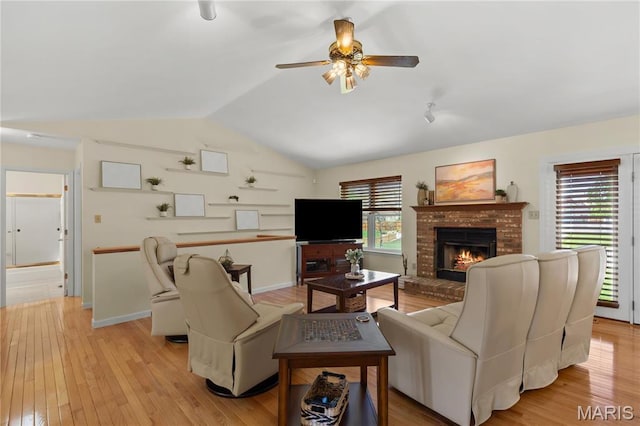 living area featuring a fireplace, ceiling fan, lofted ceiling, light wood-style floors, and baseboards