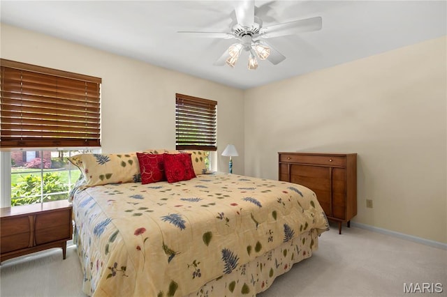 bedroom with light colored carpet, baseboards, and ceiling fan