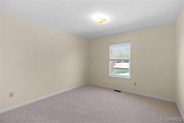 spare room featuring light carpet and baseboards