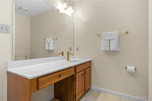 bathroom with baseboards, vanity, and toilet