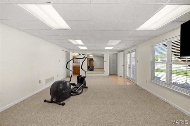 exercise area featuring light colored carpet, a drop ceiling, and baseboards