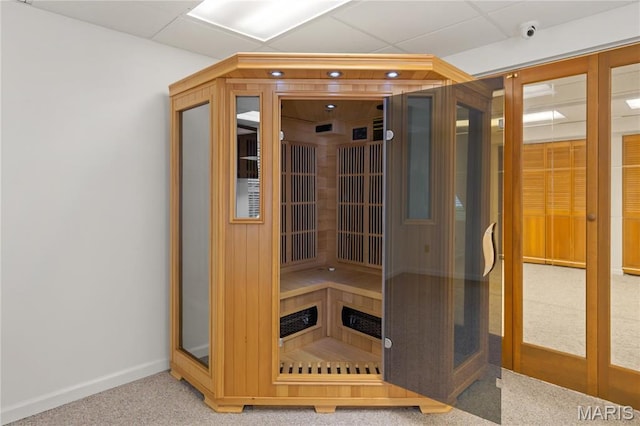 relaxing sauna featuring baseboards and carpet flooring