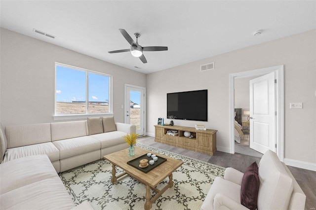 living room featuring a ceiling fan, baseboards, and wood finished floors