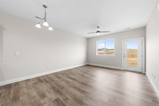 unfurnished room with wood finished floors, ceiling fan, a chandelier, and baseboards