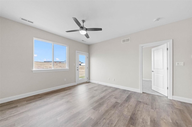 spare room with wood finished floors, a ceiling fan, and baseboards