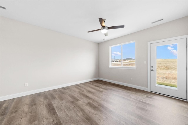 spare room featuring wood finished floors, baseboards, and a ceiling fan