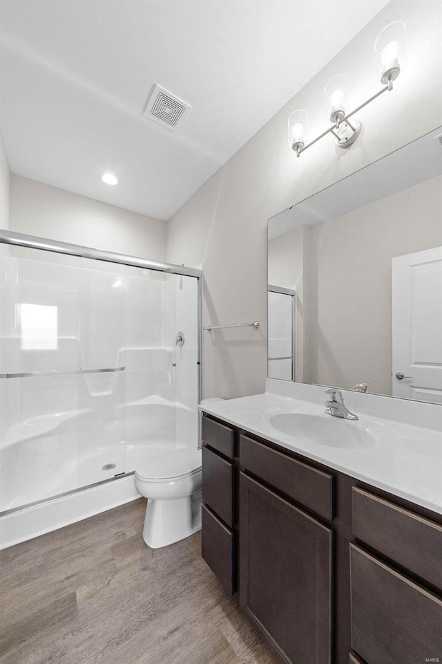 full bath featuring a shower stall, wood finished floors, toilet, vanity, and recessed lighting