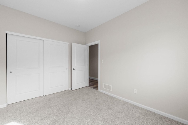 unfurnished bedroom with carpet, a closet, and baseboards