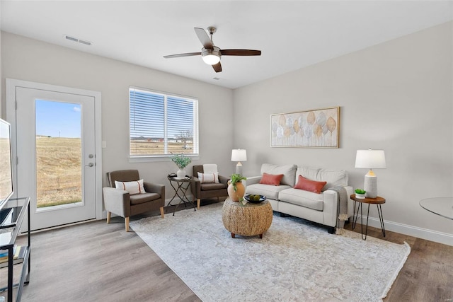 living room featuring wood finished floors, ceiling fan, and baseboards