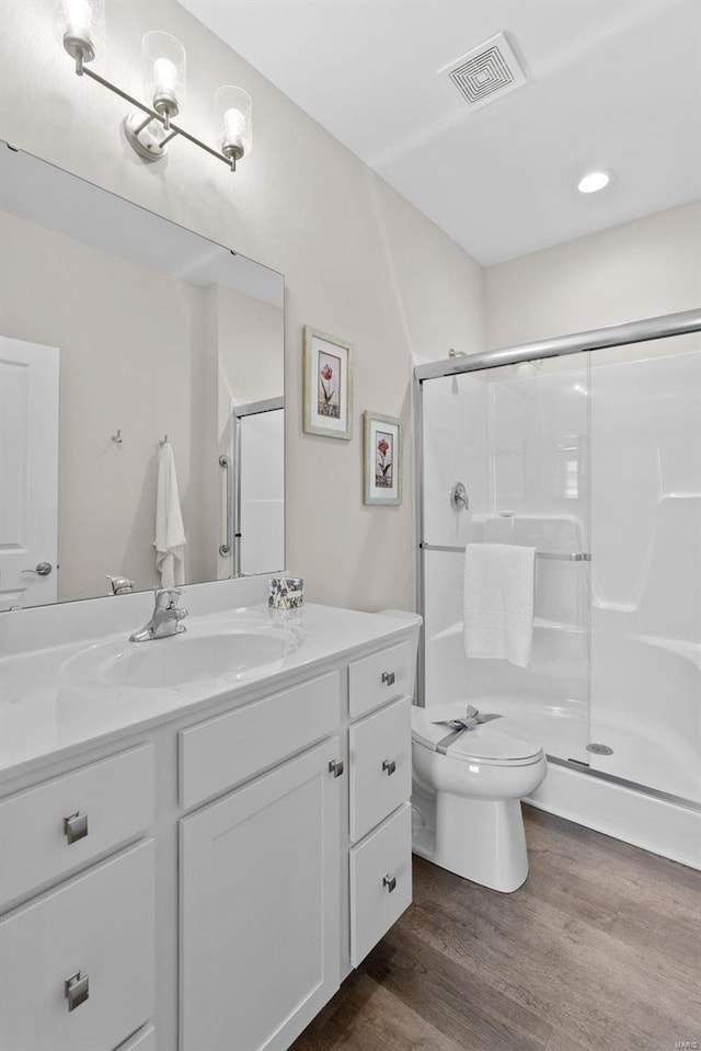 full bathroom featuring wood finished floors, a shower stall, vanity, and toilet