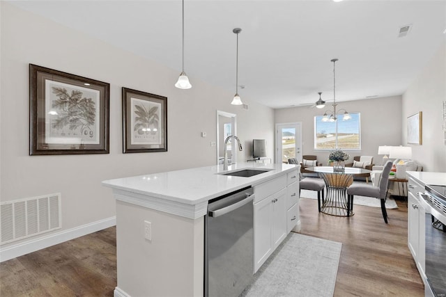kitchen with appliances with stainless steel finishes, a sink, light wood finished floors, open floor plan, and white cabinets