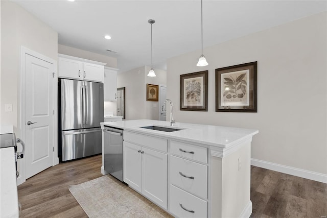 kitchen featuring stainless steel appliances, a sink, wood finished floors, an island with sink, and white cabinetry