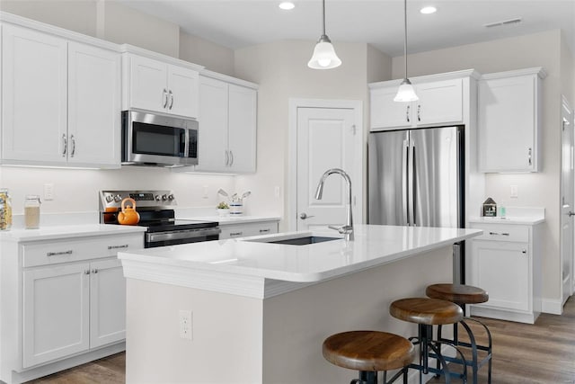 kitchen with stainless steel appliances, a sink, a center island with sink, a breakfast bar area, and light wood-type flooring