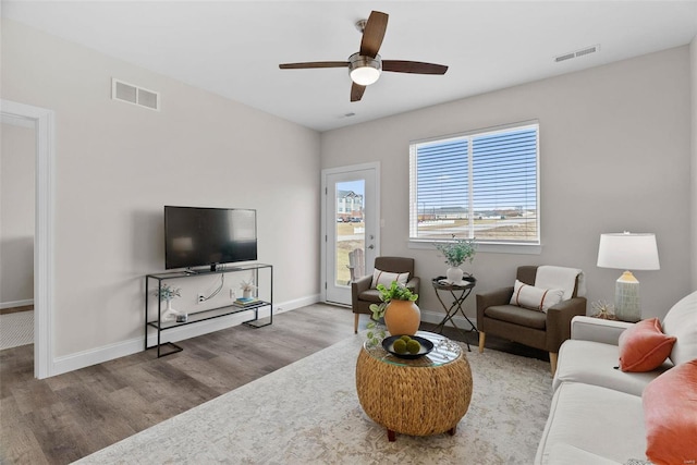 living area featuring wood finished floors, ceiling fan, and baseboards