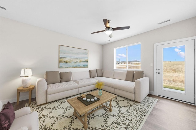 living area featuring wood finished floors, baseboards, and ceiling fan