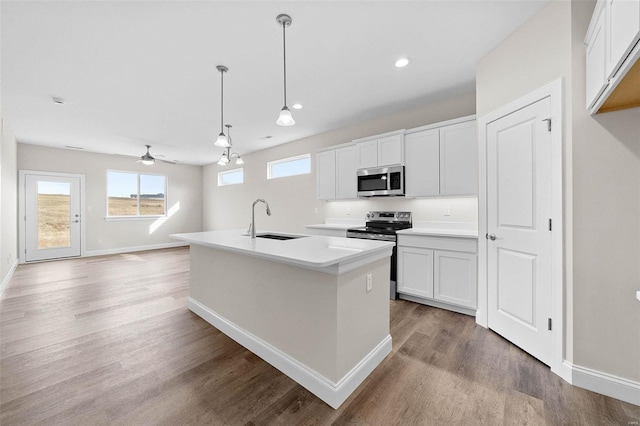 kitchen featuring stainless steel appliances, a sink, light wood-type flooring, baseboards, and white cabinetry