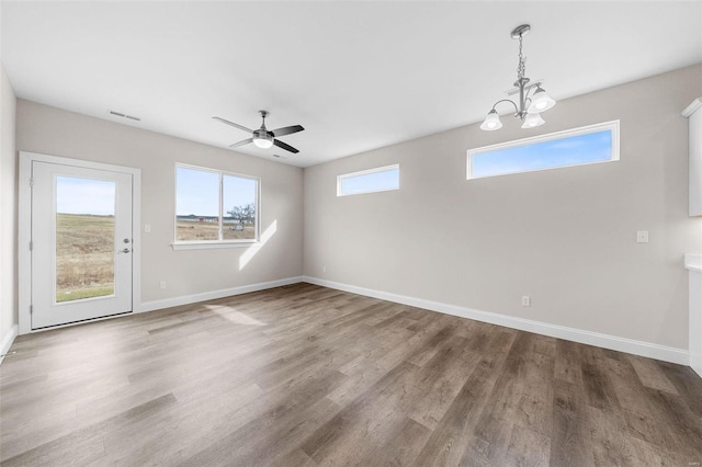unfurnished dining area with baseboards, a chandelier, wood finished floors, and a ceiling fan