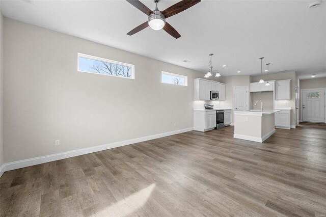 unfurnished living room featuring baseboards, light wood-style flooring, ceiling fan, recessed lighting, and a sink