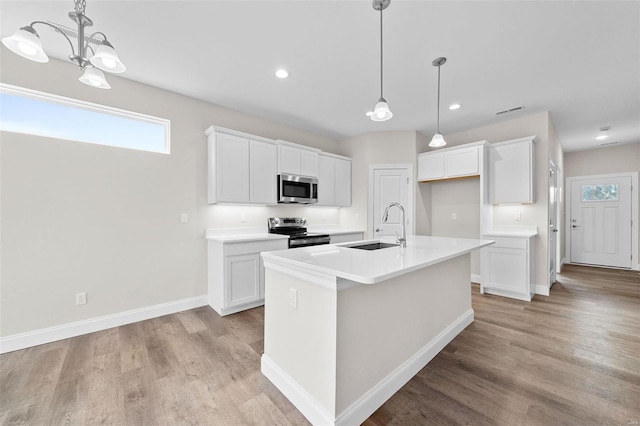 kitchen with appliances with stainless steel finishes, a sink, light wood-type flooring, white cabinetry, and recessed lighting