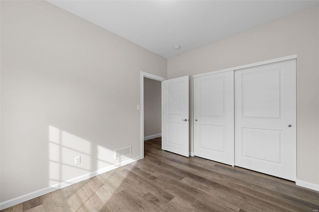 unfurnished bedroom featuring wood finished floors, baseboards, and a closet