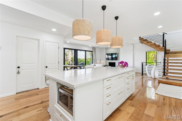 2510 N 89th St, Caseyville, IL 62232 - kitchen with stainless steel microwave, white cabinetry, light wood-style floors, plenty of natural light, and recessed lighting