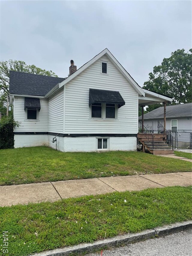 4947 Rosalie St, Saint Louis, MO 63115 - view of side of property with a yard, a chimney, covered porch, and roof with shingles