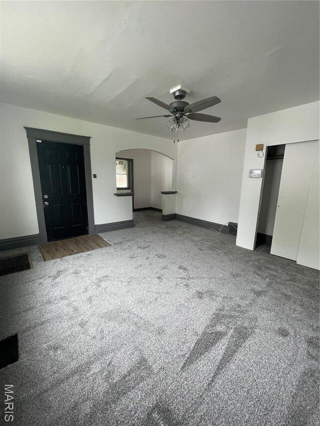 4947 Rosalie St, Saint Louis, MO 63115 - unfurnished living room with a ceiling fan, carpet floors, arched walkways, and baseboards