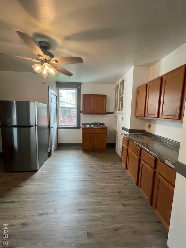 4947 Rosalie St, Saint Louis, MO 63115 - kitchen featuring freestanding refrigerator, brown cabinetry, wood finished floors, dark countertops, and a ceiling fan