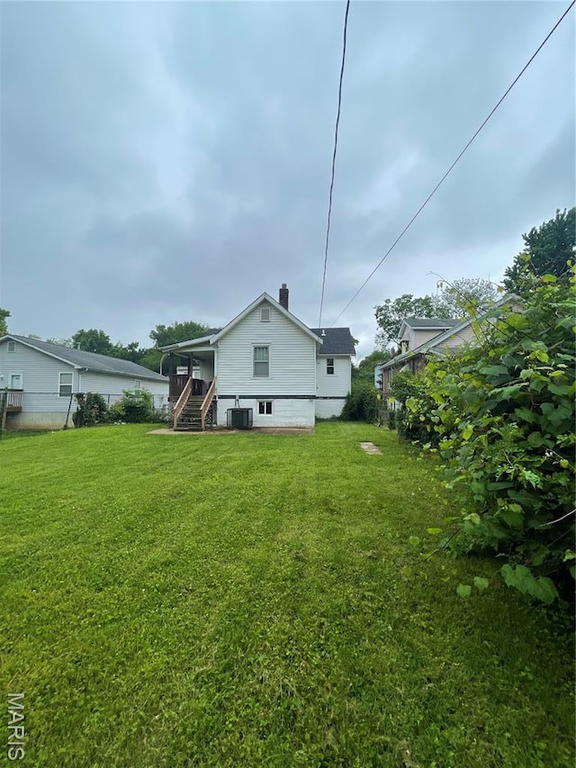 4947 Rosalie St, Saint Louis, MO 63115 - back of house with central air condition unit, a yard, a sunroom, and stairway