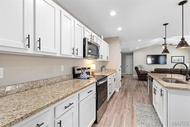 135 Mary Catherine, Waynesville, MO 65583 - kitchen with stainless steel appliances, light wood-style flooring, white cabinetry, vaulted ceiling, and decorative light fixtures