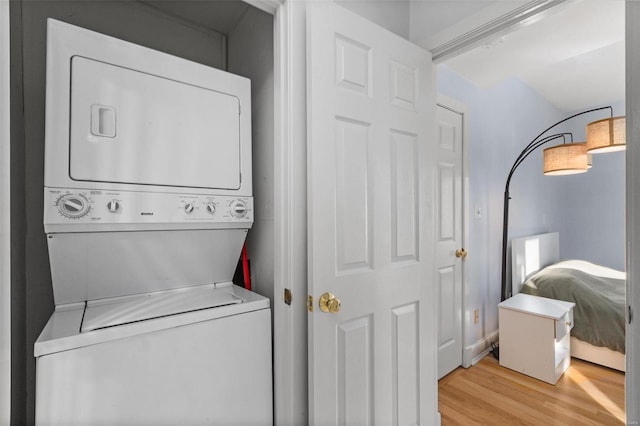 clothes washing area with estacked washer and dryer and wood finished floors