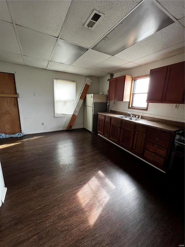 1642 3rd St, Madison, IL 62060 - kitchen featuring freestanding refrigerator, dark wood-type flooring, a sink, a drop ceiling, and baseboards