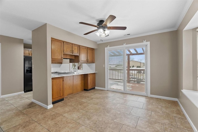 kitchen with black fridge, brown cabinets, light countertops, ceiling fan, and crown molding