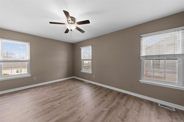 empty room featuring wood finished floors, baseboards, and ceiling fan