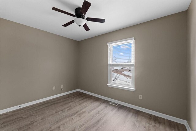 spare room featuring wood finished floors, baseboards, and a ceiling fan