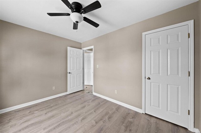 unfurnished bedroom with wood finished floors, baseboards, and a ceiling fan