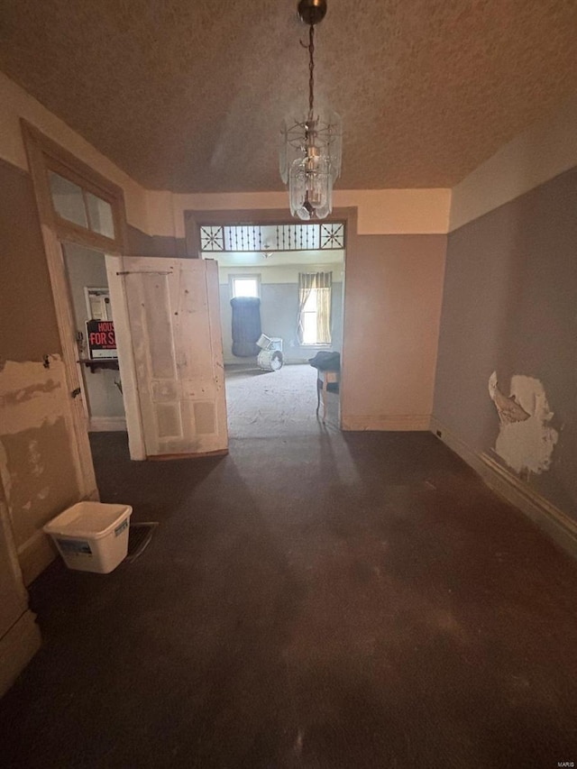 1809 Chestnut St, Hannibal, MO 63401 - unfurnished dining area with a chandelier, baseboards, and a textured ceiling