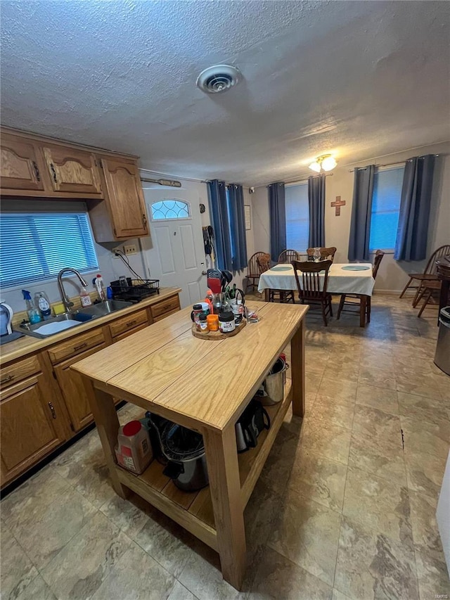 13 Jo Ab Ln, Williamsville, MO 63967 - kitchen featuring a sink, brown cabinetry, a textured ceiling, open shelves, and light stone finish flooring