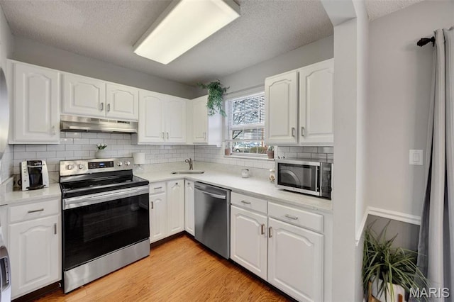 1419 Bluebird Ter, Saint Louis, MO 63144 - kitchen with stainless steel appliances, under cabinet range hood, a textured ceiling, white cabinets, and a sink