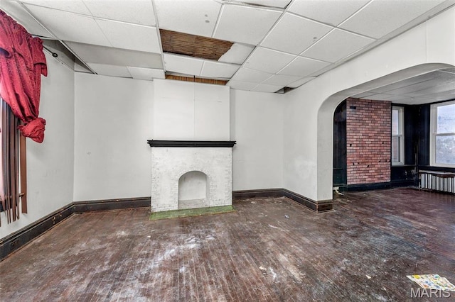 7307 Minnesota Ave, Saint Louis, MO 63111 - unfurnished living room featuring a paneled ceiling, a fireplace, baseboards, hardwood / wood-style floors, and arched walkways